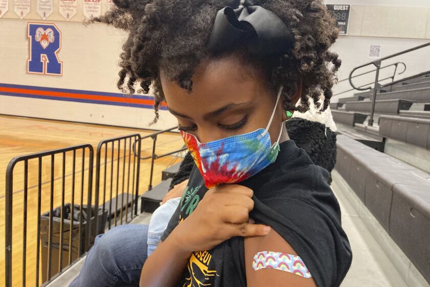 Solome Walker, 9, looks down at her bandage after getting her first Pfizer COVID-19 shot at a vaccination clinic for young students at Ramsey Middle School on Saturday, Nov. 13, 2021 in Louisville, Ky. Scientists say vaccinating kids against COVID-19 should not only slow the spread of the coronavirus but also help prevent potentially-dangerous variants from emerging. Each new infection brings another opportunity for the virus to mutate and evolve dangerous new traits. (AP Photo/Laura Ungar)