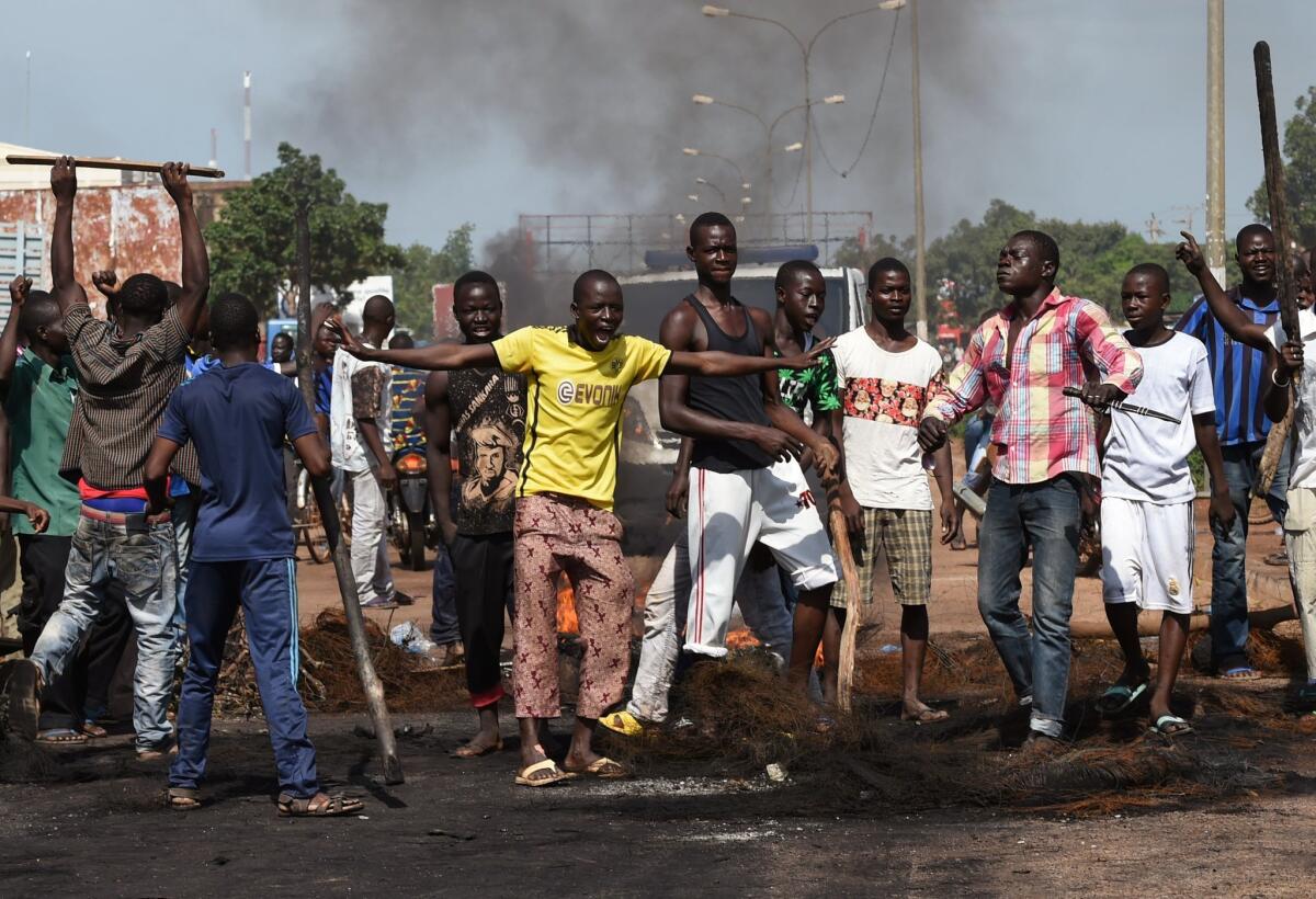 Demonstrators shout slogans next to burning tree branches in Ouagadougou, the capital of Burkina Faso, during a protest against a regional proposal to give amnesty to coup leaders.