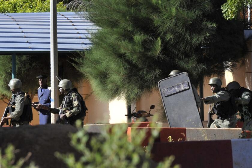 Malian troops take position outside the Radisson Blu hotel in Bamako. Gunmen went on a shooting rampage at the luxury hotel in Mali's capital, seizing 170 guests and staff. At least three people are dead.