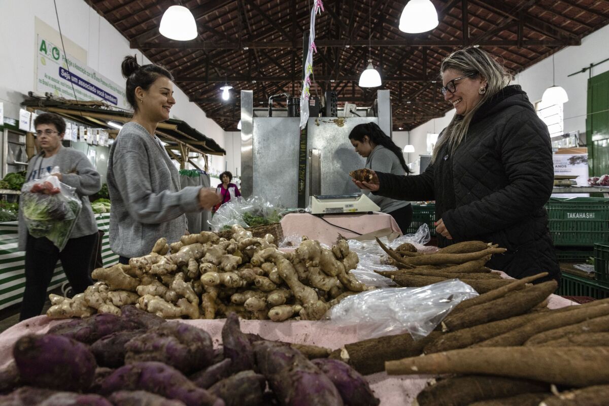Monica dos Santos, right, sells produce at Agua Branca Park's organic products fair. She is selling ginger, yuca and yam produced by her father, Joaquim dos Santos.