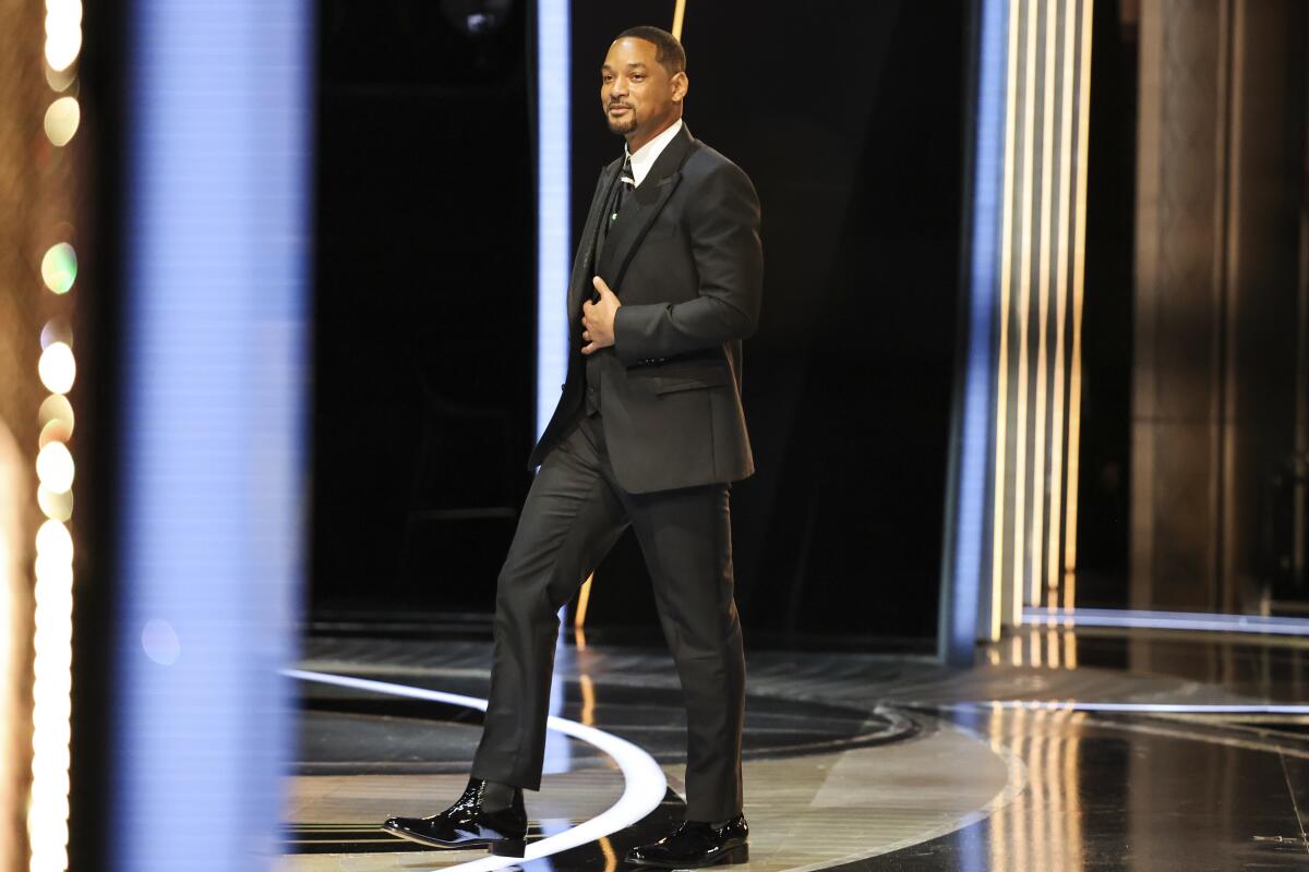 A man in a black suit steps onto a stage