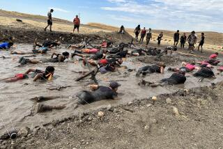 Tough Mudder participants crawl through the mud under barbed wire at an event held at the Sonoma Raceway on Aug. 20, 2023.