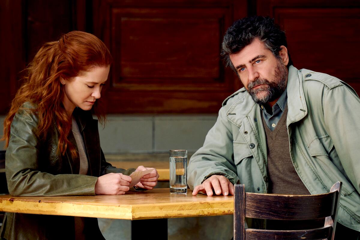 Sarah Drew and Asterios Peltekis sit at a table in “Stolen By Their Father” on Lifetime.
