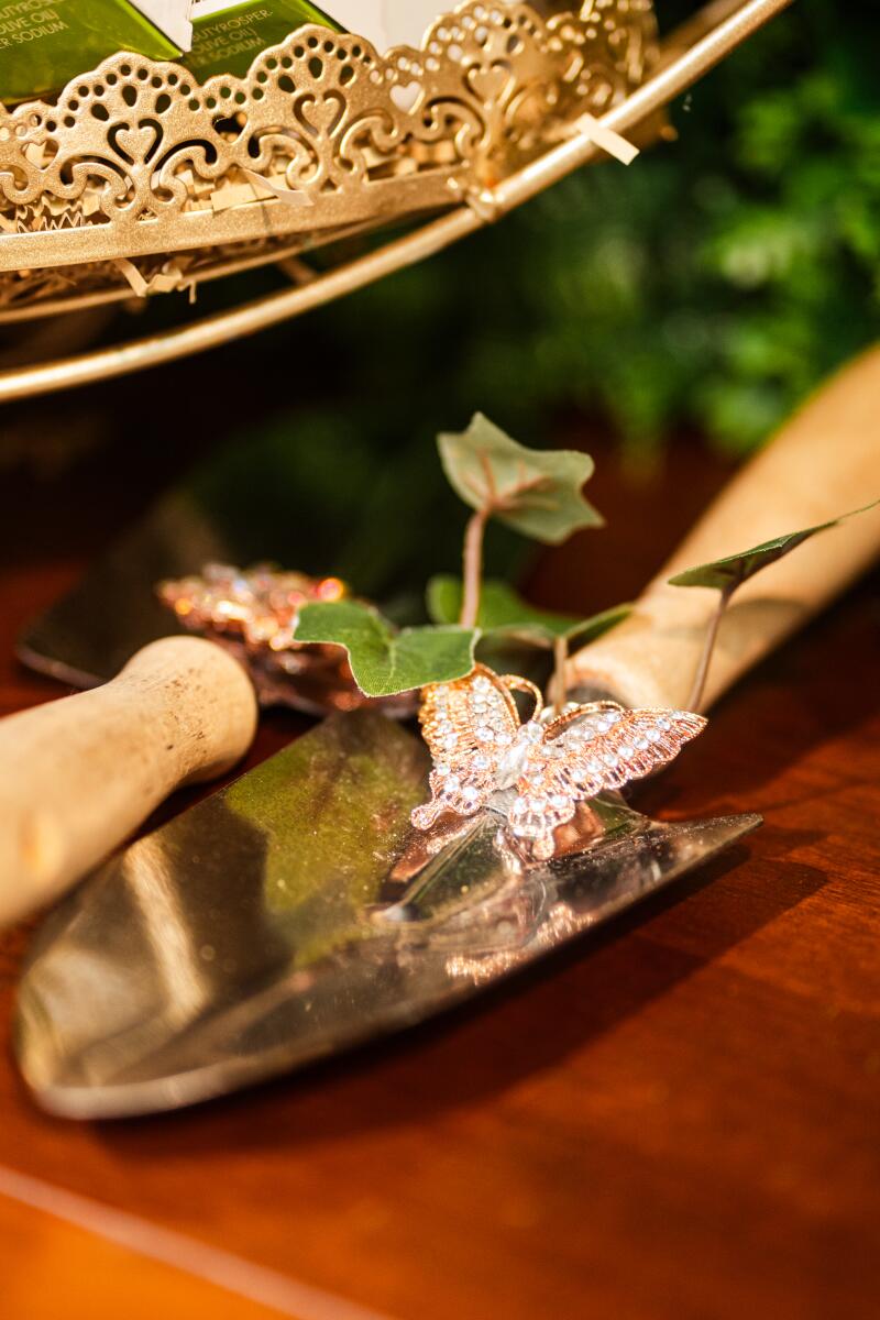 A trowel with a small plant rests on a wooden table