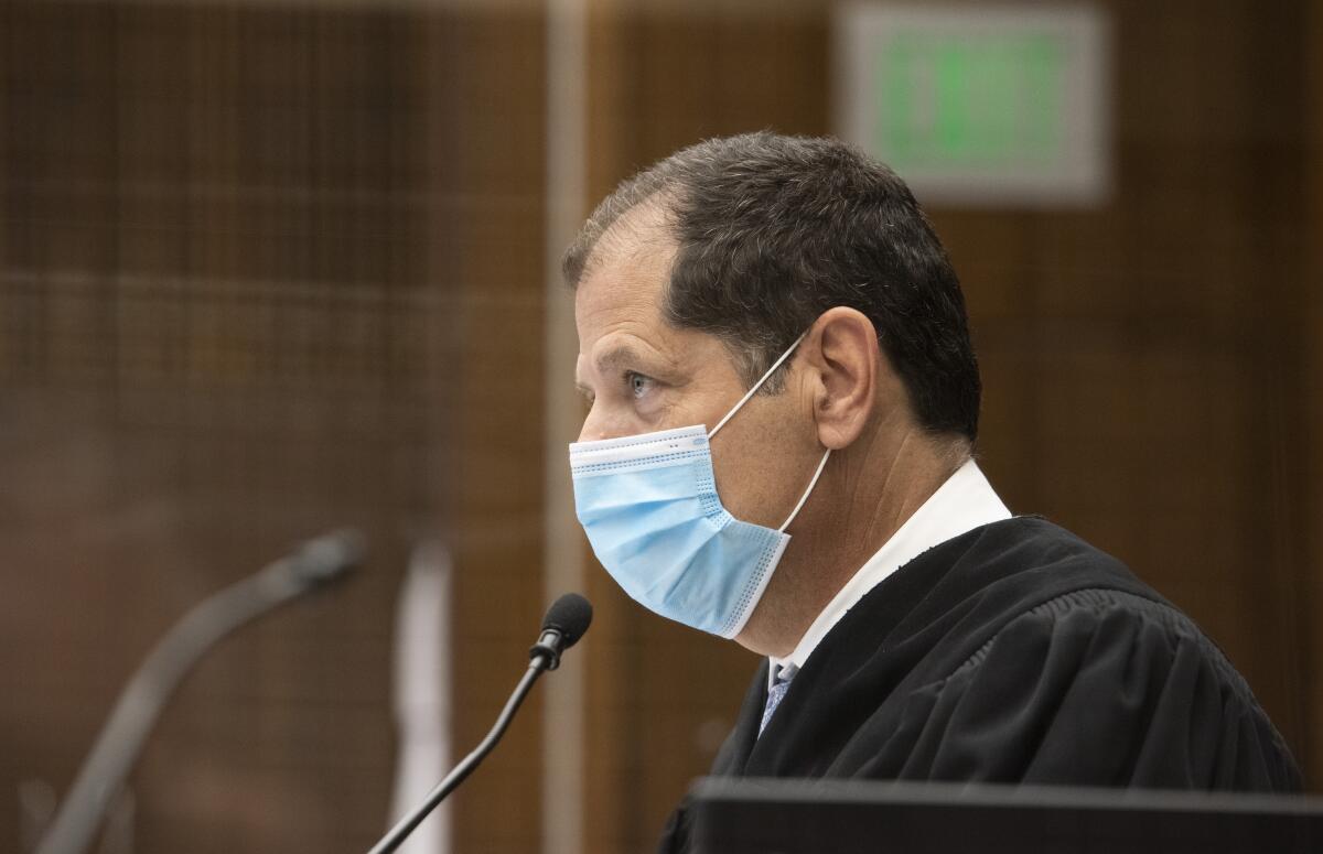 A judge, in robes, wears a mask.