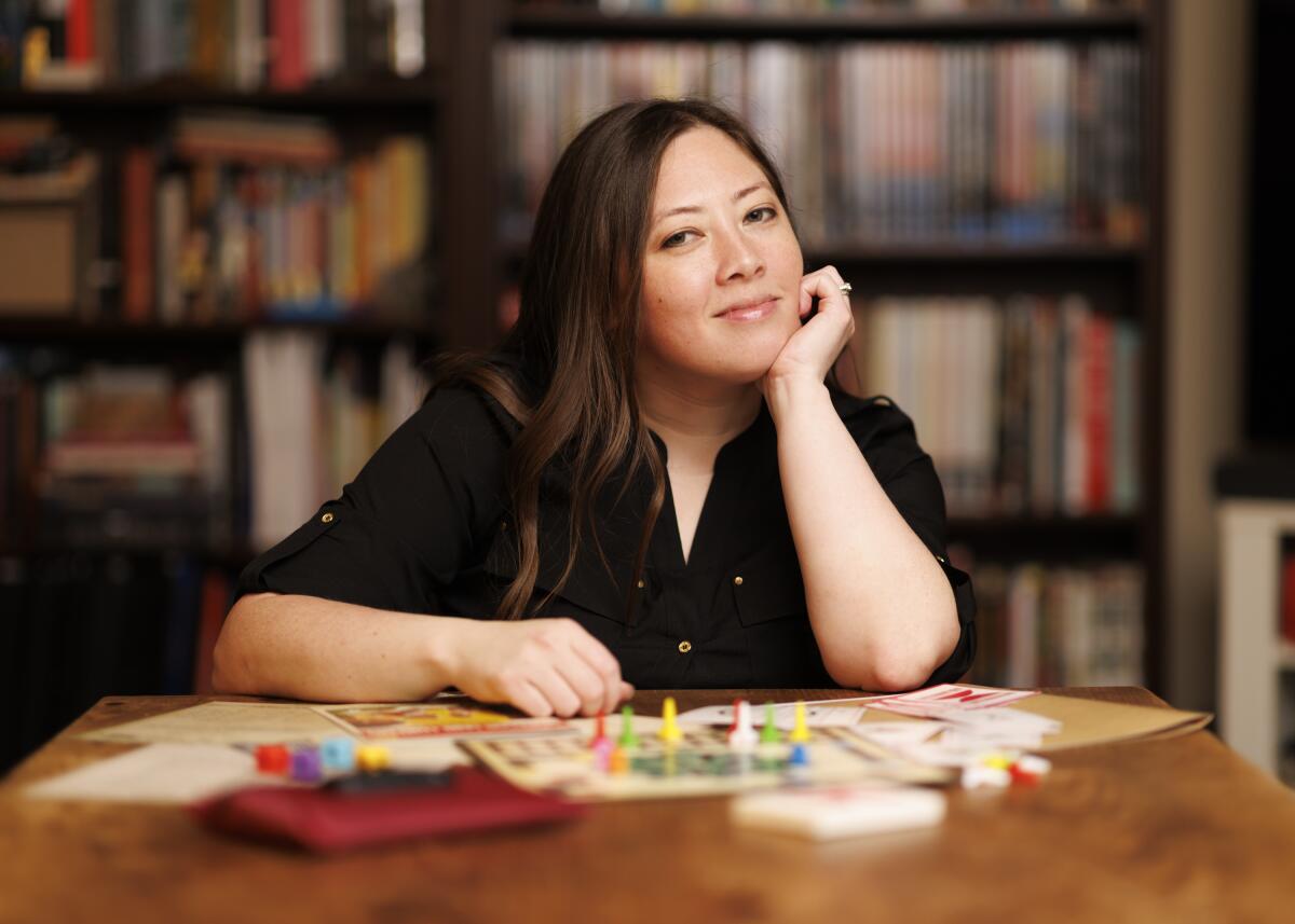 Lauren Bello sits at a table with her game, "The Morrison Game Factory," spread out in front of her