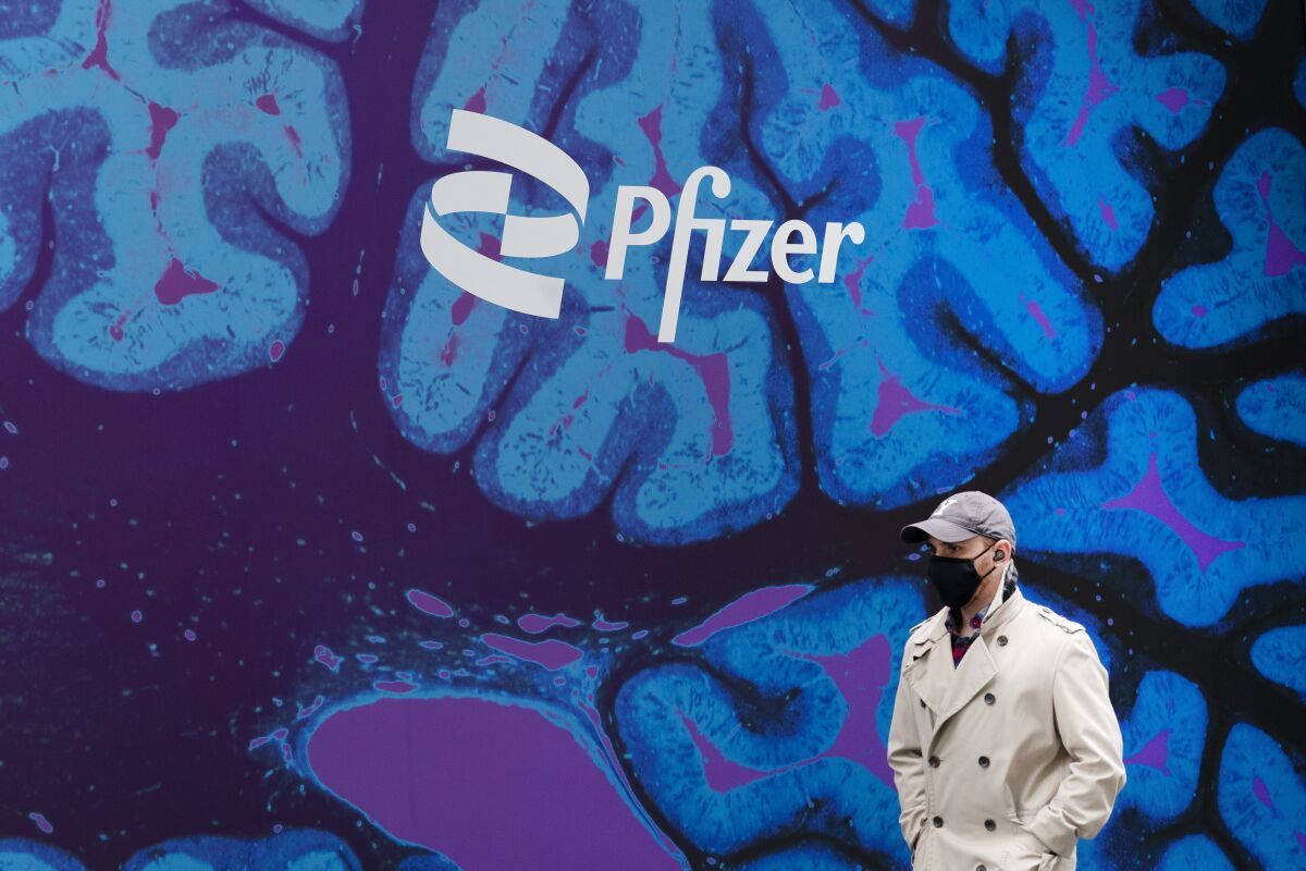 FILE - A man walks by Pfizer headquarters, Friday, Feb. 5, 2021 in New York. Pfizer is spending more than $11 billion to buy the remaining portion of migraine treatment maker Biohaven Pharmaceuticals it does not already own. The New York drugmaker said Tuesday, May 10, 2022, it will pay $148.50 in cash for each share of Biohaven, which makes Nurtec ODT for treating and preventing migraines and has another nasal spray under development. (AP Photo/Mark Lennihan, File)