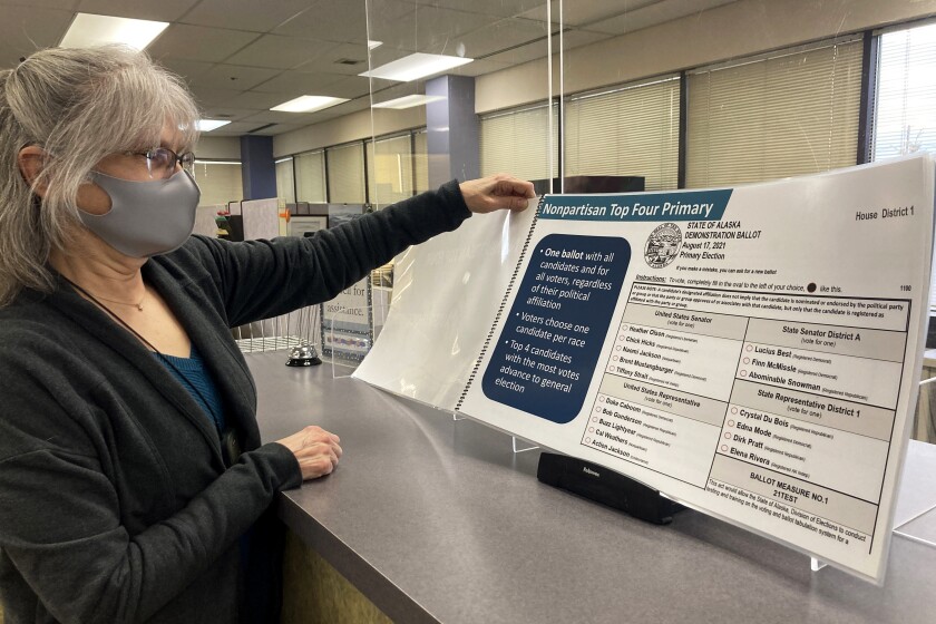 Deborah Moody, an administrative clerk at the Alaska Division of Elections office in Anchorage, Alaska, looks at an oversized booklet explaining election changes in the state on Jan. 21, 2022. Alaska elections will be held for the first time this year under a voter-backed system that scraps party primaries and sends the top four vote-getters regardless of party to the general election, where ranked choice voting will be used to determine a winner. No other state conducts its elections with that same combination. (AP Photo/Mark Thiessen)