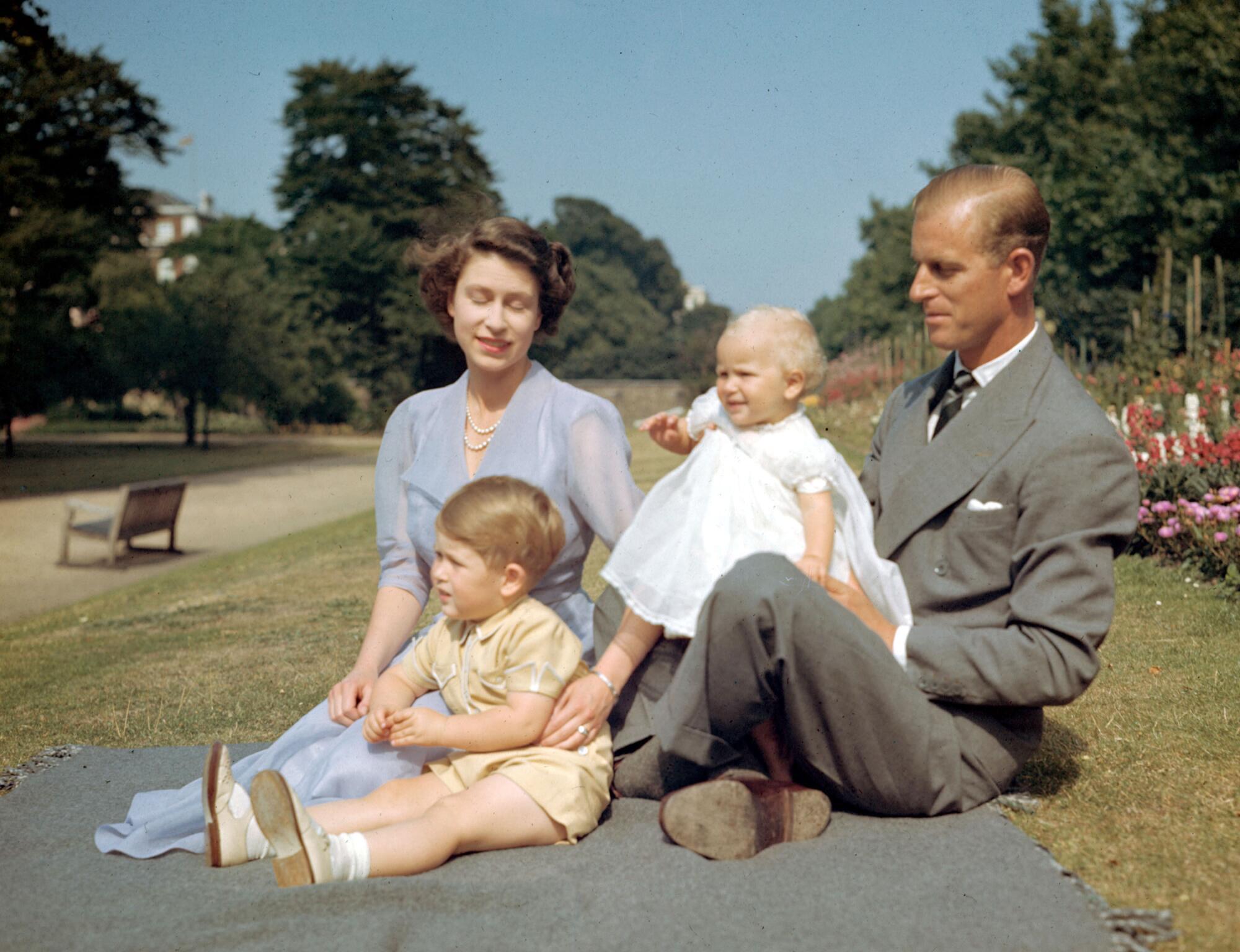 The royal family sits outside in 1951 with two small children