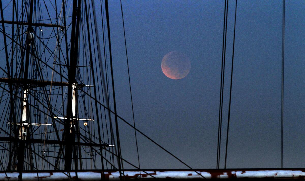 DECEMBER 10, 2011. SAN DIEGO, CA. As dawn breaks over the tall ships at the San Diego Maritime Museum, the setting moon begins to emerge from Earth's shadow after a total eclipse on December 10, 2011. (Don Bartletti / Los Angeles Times)
