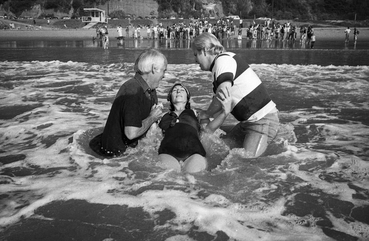 November 1976: Jack McKee and Rev. Kenn Gulliksen baptize Diane Hunter in the surf at Will Rogers State Beach.