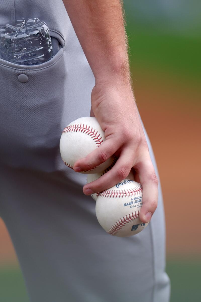 Bir Dodgers oyuncusu elinde beyzbol topları tutuyor.