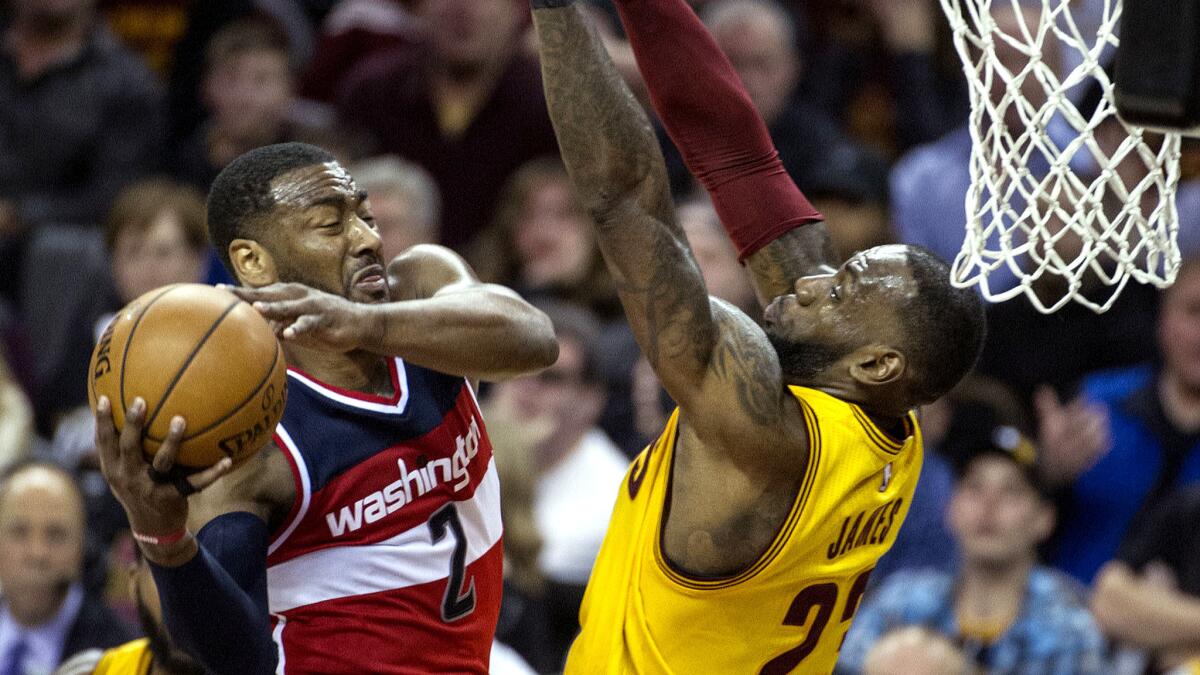 Wizards point guard John Wall powers his way for a layup against Cavaliers forward LeBron James during the first half Saturday. (Phil Long / Associated Press)