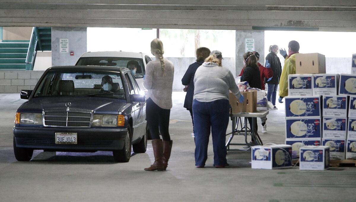 Food pantry volunteers load food into the trunk of a motorist at Glendale Community College on Tuesday, April 7, 2020.