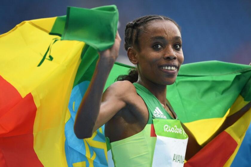 Almaz Ayana of Ethiopia runs with her country's flag after winning a gold medal and setting a world record in the women's 10,000 meters on Aug. 12.