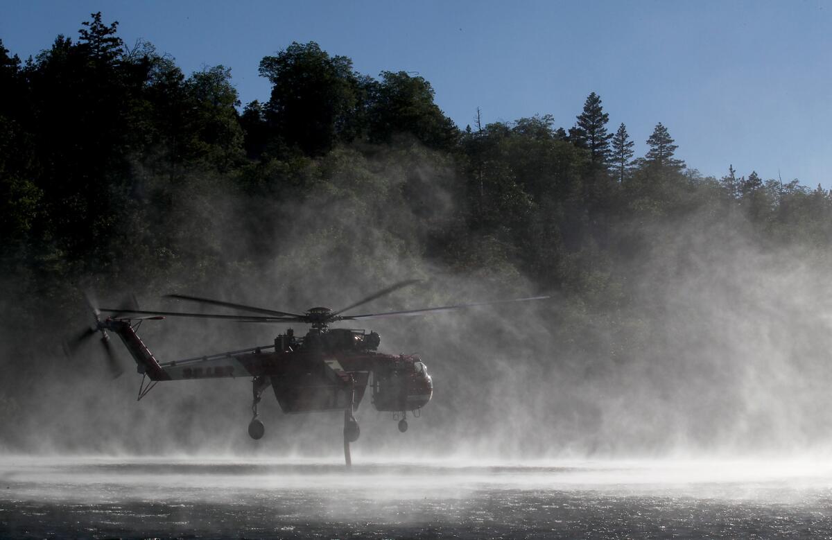 A firefighting helicopter draws water from Jenks Lake near Big Bear on June 18. Aircraft fighting the fire were temporarily grounded when a drone was spotted in a tanker's flight path.
