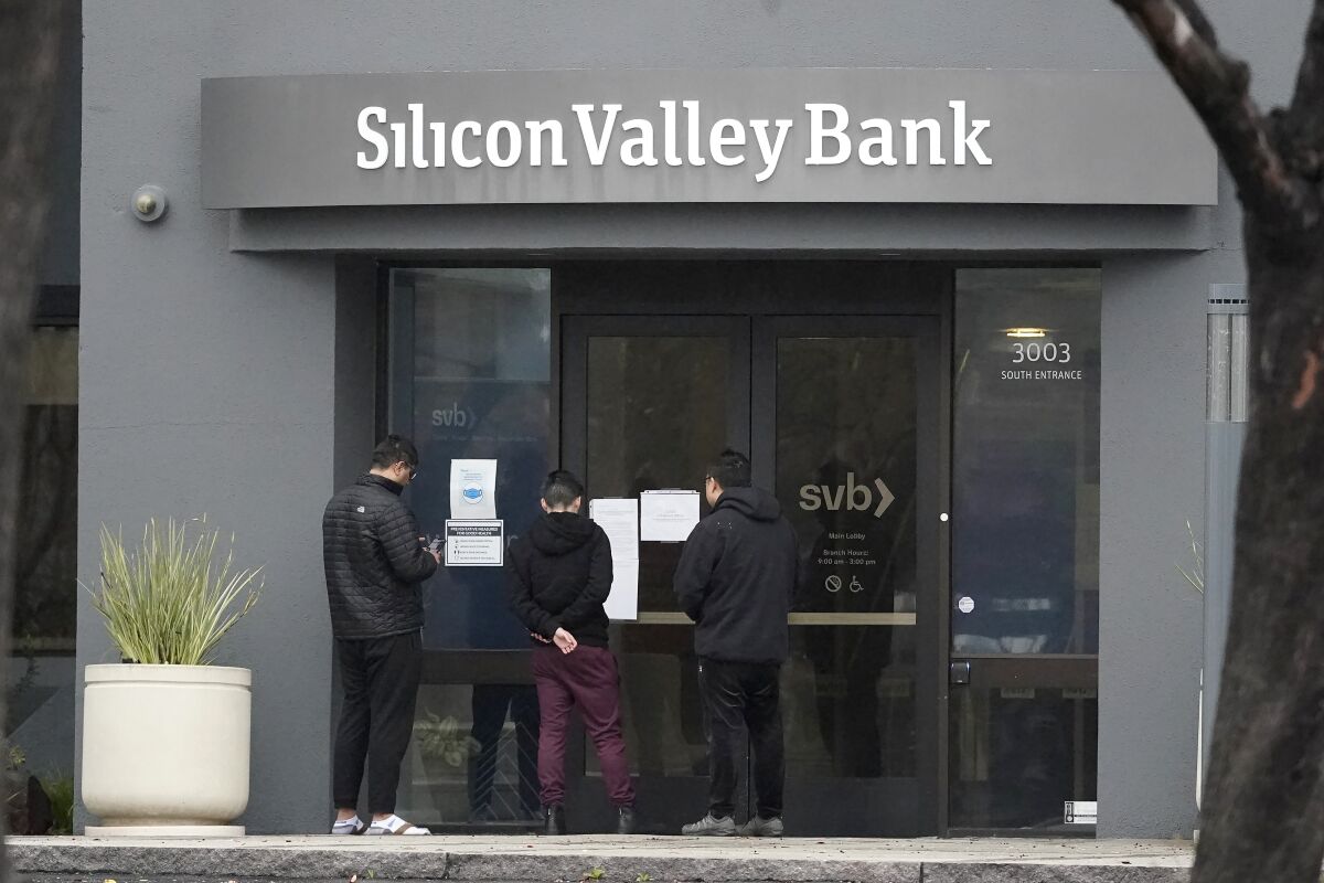 Three people standing outside the glass doors of Silicon Valley Bank