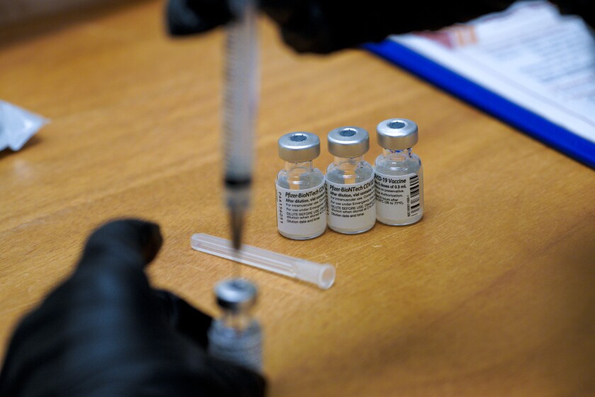 A pharmacist draws the vaccine into syringes 