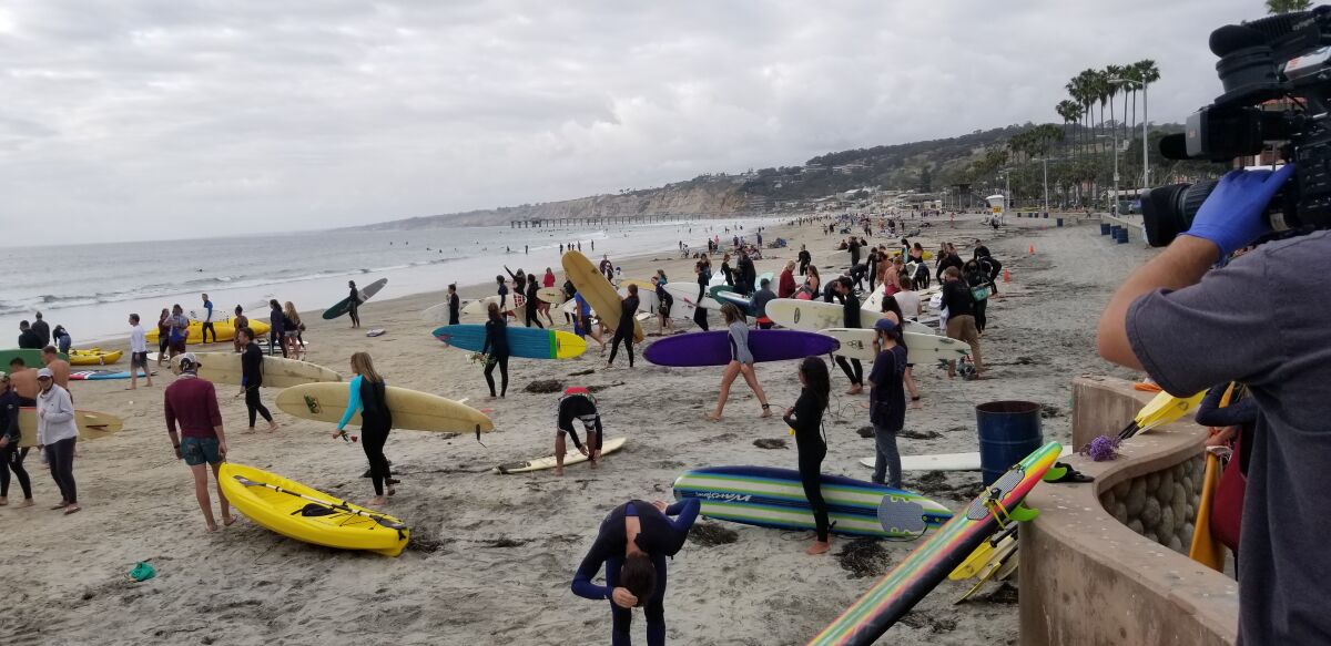People head out on surfboards, paddleboards and kayaks in a protest paddle-out organized by Groundswell Community Project.