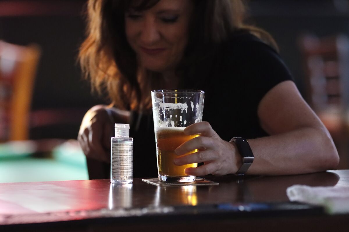 Sherry Lyon drinks a beer at Carriage House in Kearny Mesa with her hand santizer within easy reach.