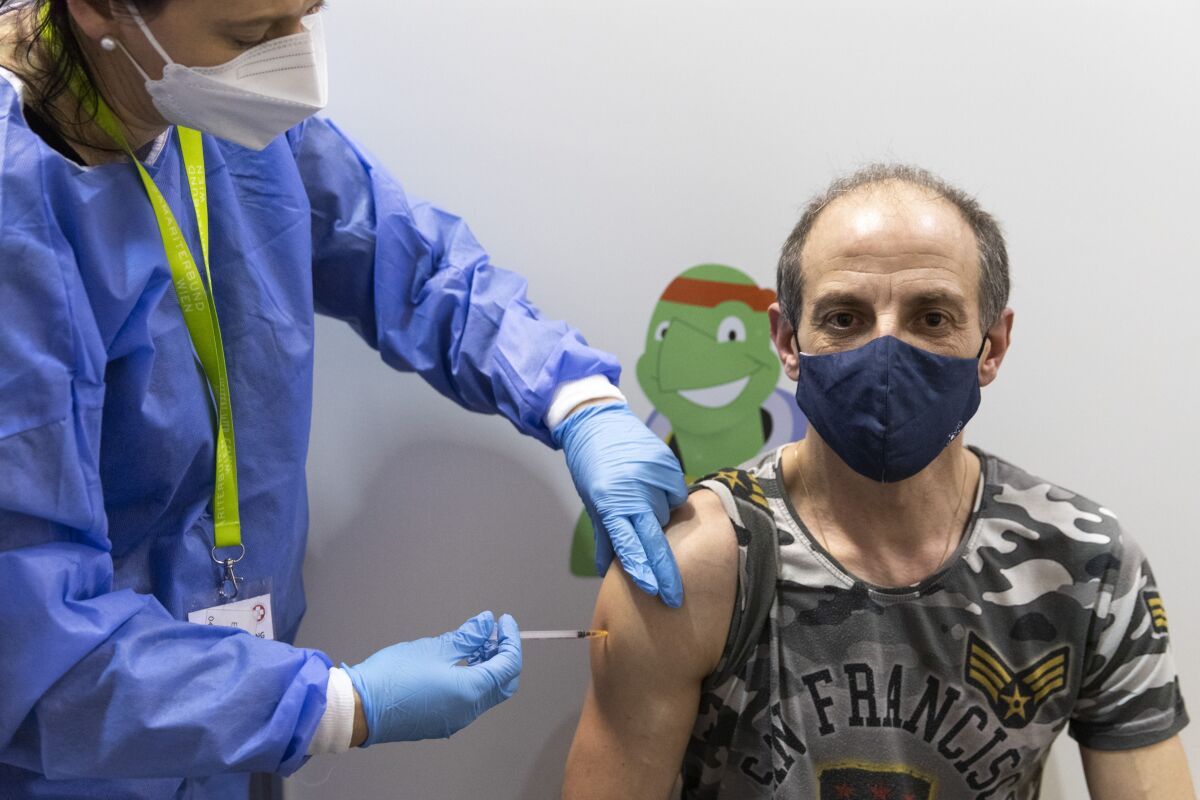 A person gets vaccinated against the COVID-19 virus as the compulsory COVID-19 vaccination starts in Vienna, Austria, Friday, Feb. 4, 2022. (AP Photo/Lisa Leutner)