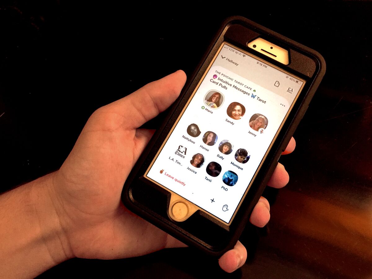 A hand holding an iPhone with a number of faces on the screen