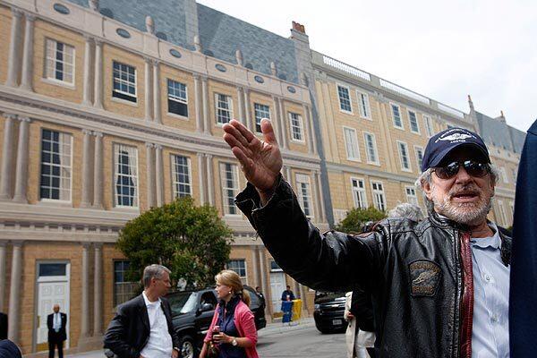 Filmmaker Steven Spielberg discusses the improvements of the new sets including the hand-painted mural facade (shown in background) along the London Square area, during a press unveiling of the newly rebuilt New York Street, which was gutted by a fire two years ago. Universal Studios Hollywood reopened the New York backlot tram tours Friday.