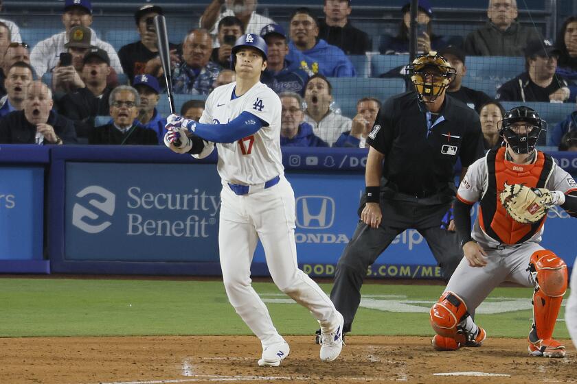 Shohei Ohtani watches his first home run as a Dodger fly well over the fence.
