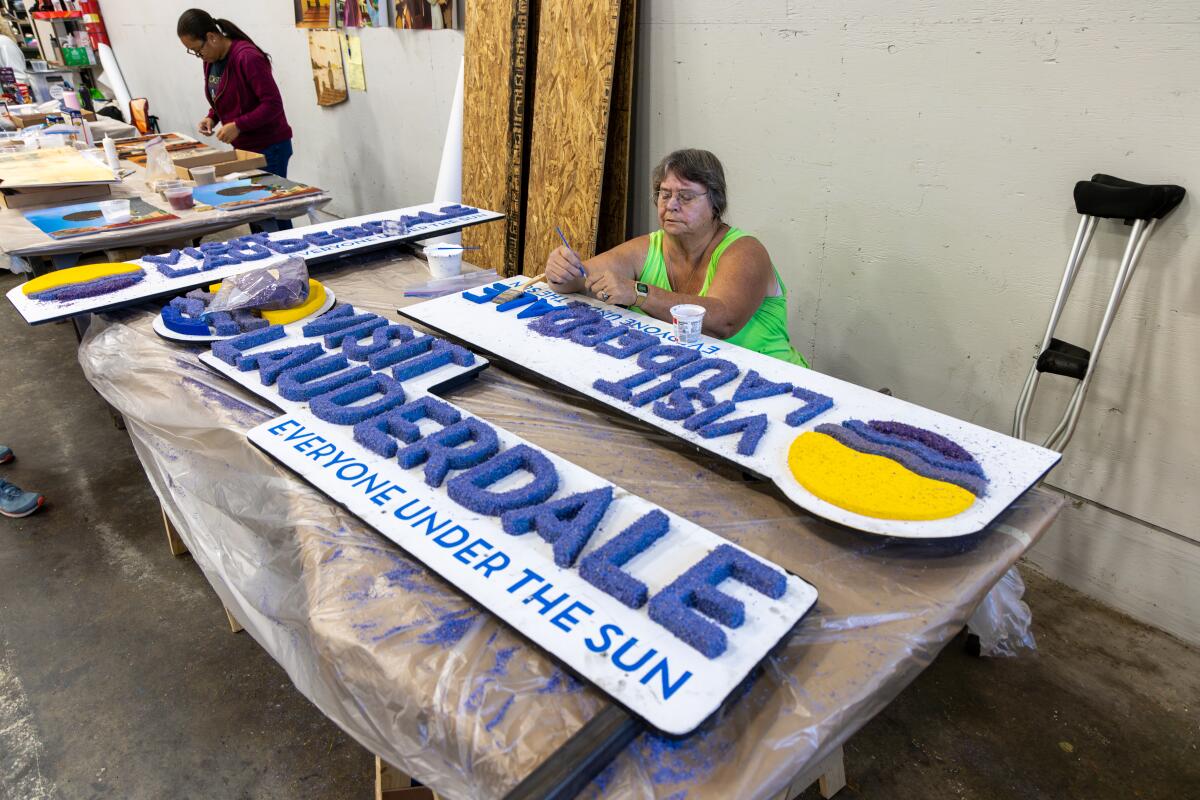 Laura Green works on sign, for Lauderdale float for Rose parade "Visit Lauderdale -