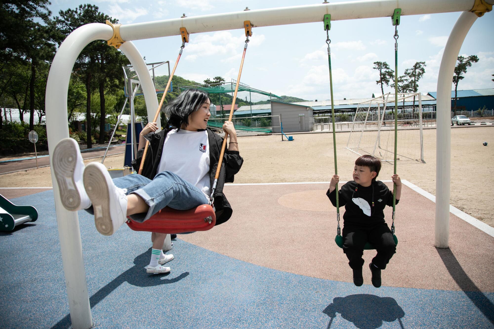 A woman and her son ride swings at Dochang Elementary.