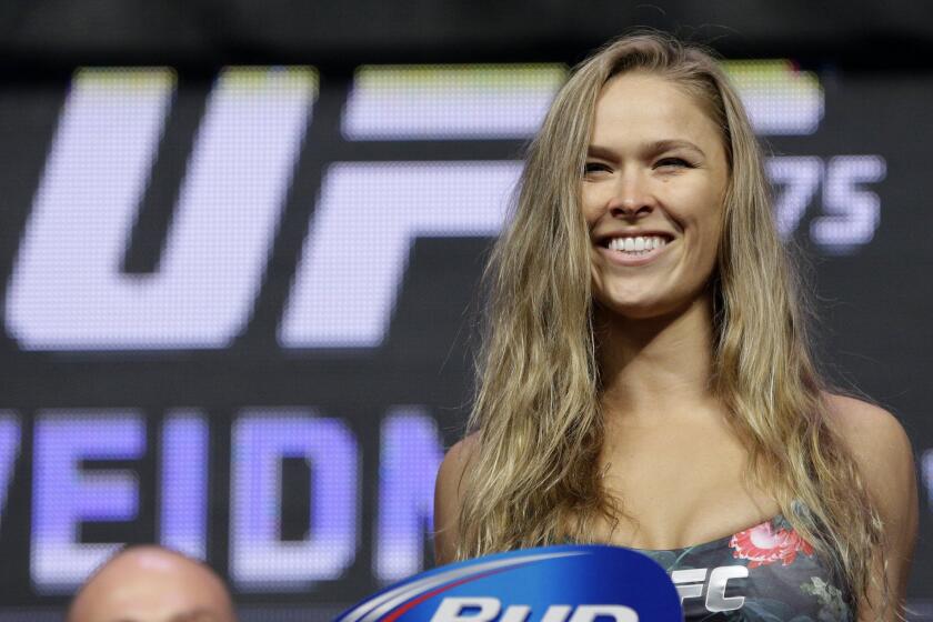 Former women's bantamweight champion Ronda Rousey stands on the scale during a weigh-in for the UFC 175 in Las Vegas on July 4, 2014.