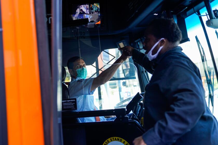 LOS ANGELES, CA - JULY 10: Operator Jimi Pollard, right, from division 3k greets a fellow operator who stopped his bus at the stoplight and honked his horn in support as L.A. Metro bus operators protest outside of the Metro Headquarters in downtown Los Angeles on Friday, July 10, 2020 in Los Angeles, CA. L.A. Metro bus drivers are demanding hazard pay for working during the ongoing coronavirus pandemic. (Kent Nishimura / Los Angeles Times)