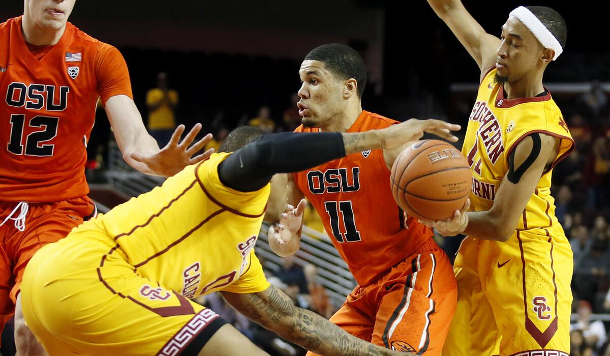 Oregon State's Malcolm Duvivier, center, attempts to get through the defense of USC's Darion Clark, left, and Jordan McLaughlin during the first half on Wednesday.