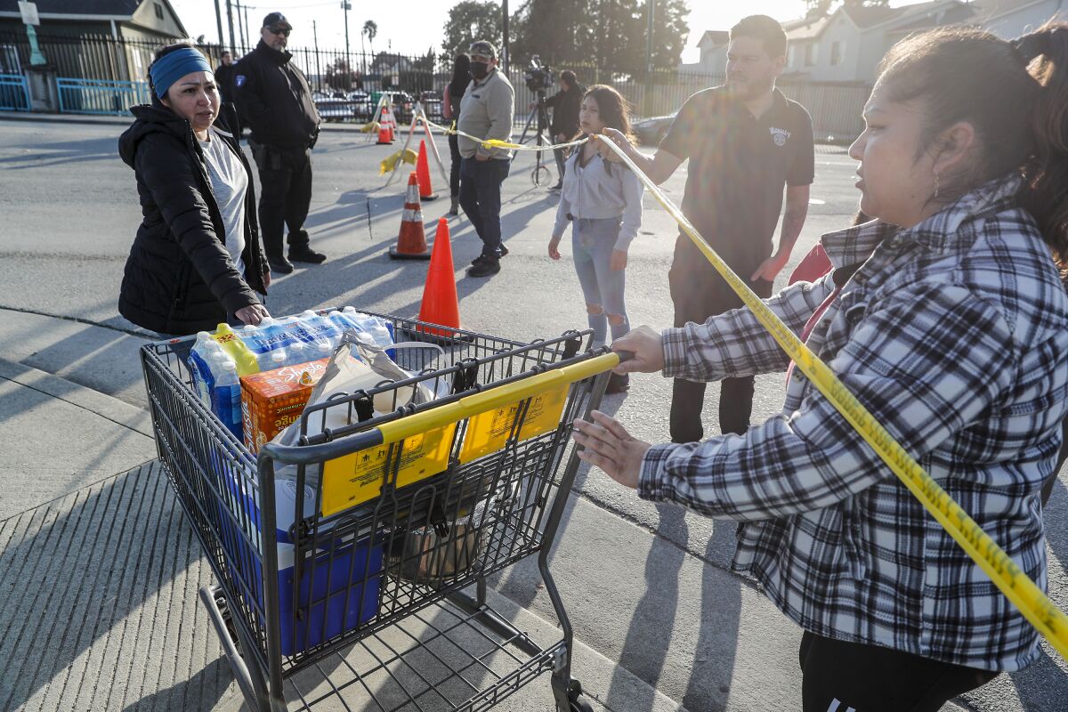 Maria Terriquez receives a shopping cart of supplies at the foot of the Pajaro River Bridge