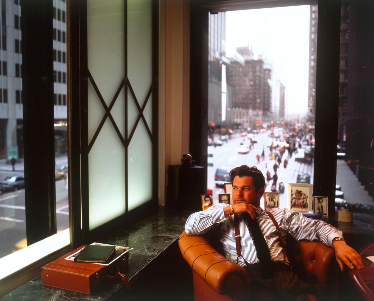 A man in a corner officer sits in a chair and looks out the window