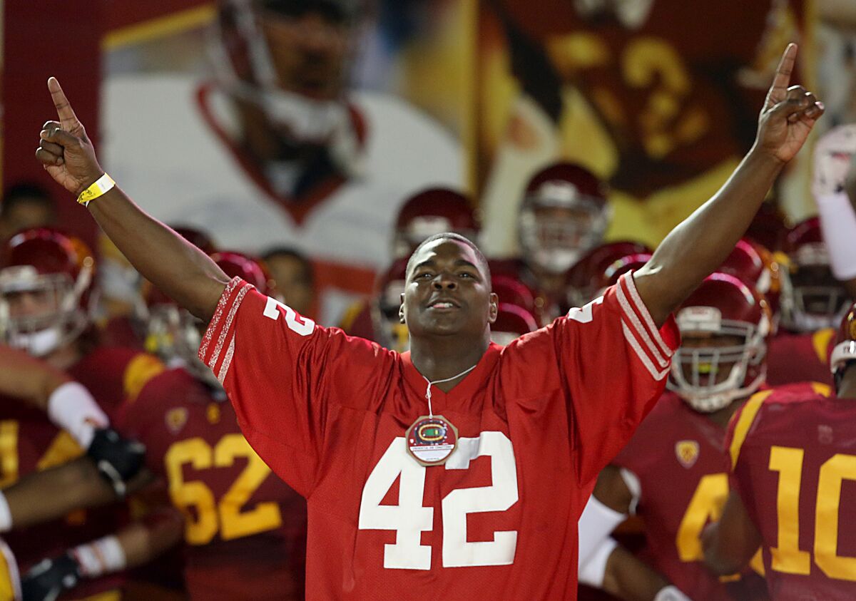 Former USC player Keyshawn Johnson in a No. 42 jersey leads the Trojan squad onto the field
