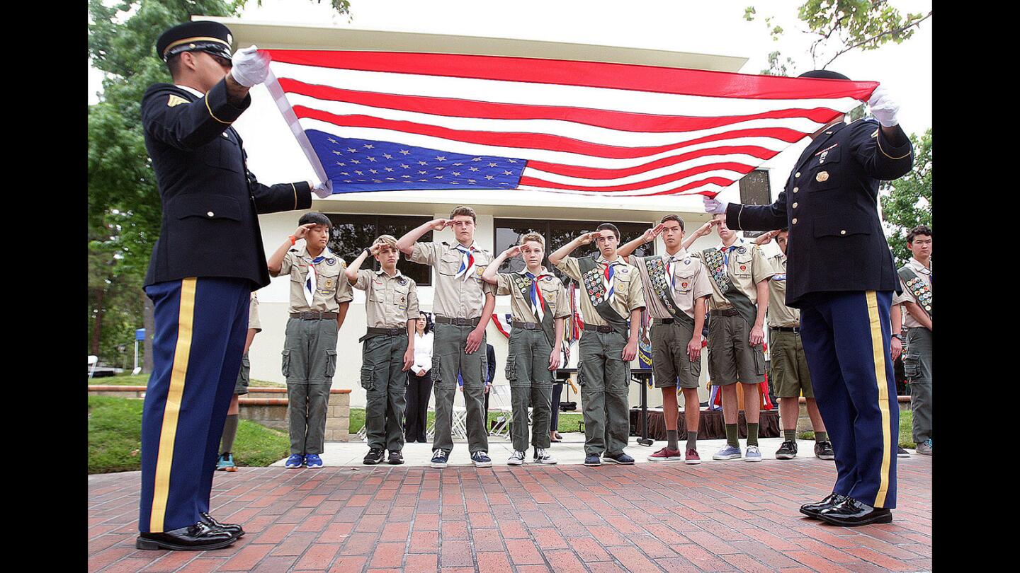 Two representatives from the California State Honor Guard, with Troop 125 Boy Scouts saluting, present an American Flag for folding at the Glendale-Montrose-Crescenta Valley Veterans Memorial outside Glendale City Hall on Monday, May 30, 2016. Once folded, the flag will be presented to the Stifter family for their son who was killed recently in Iraq, the last name added to the war memorial.