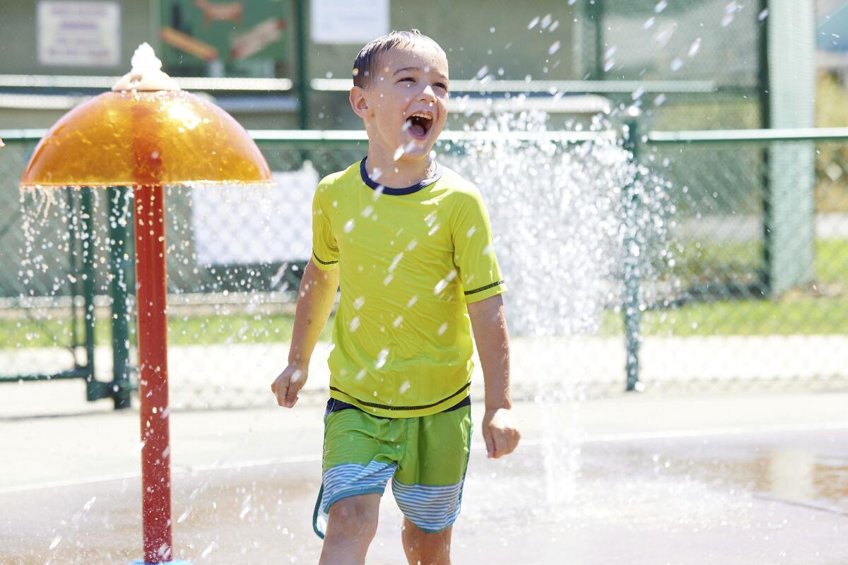 Hunter Sack, 7, runs through the water at Max Patterson park to escape from the heat in Gladstone, Ore.