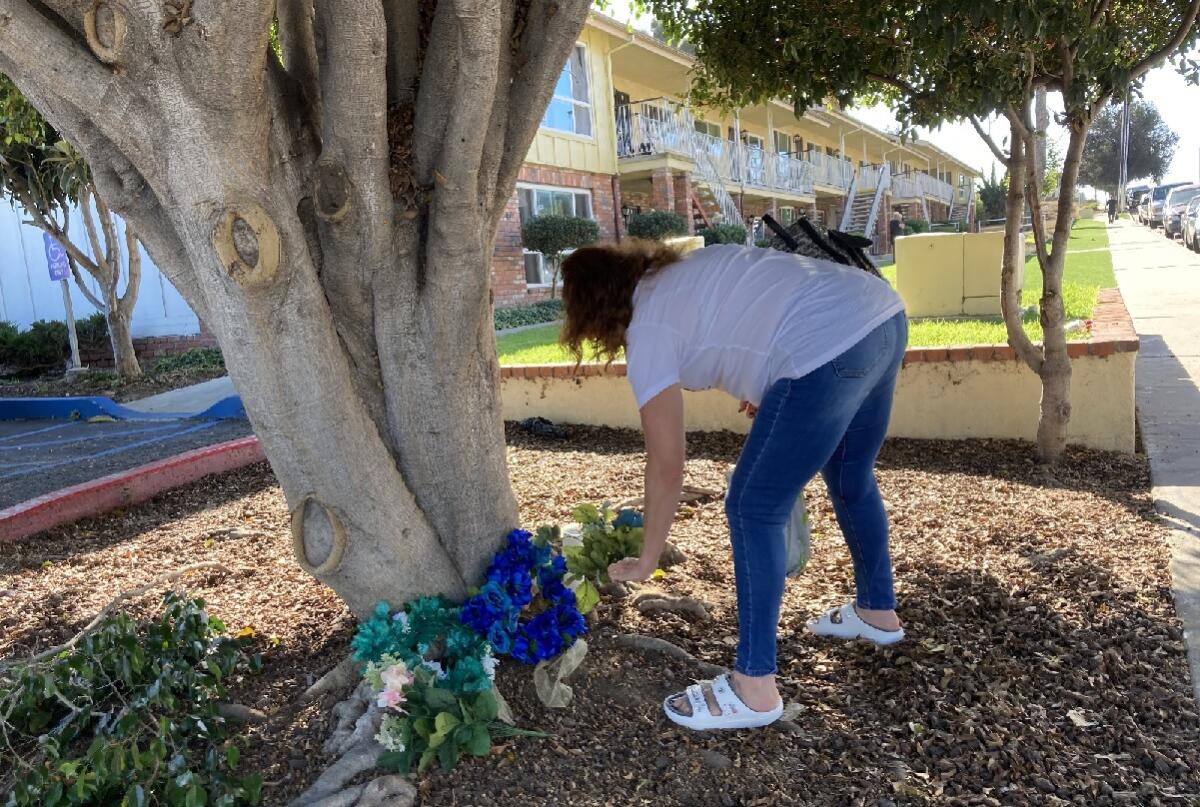 A woman places a candle and flower wreaths near the spot where two teens were fatally shot Saturday night.
