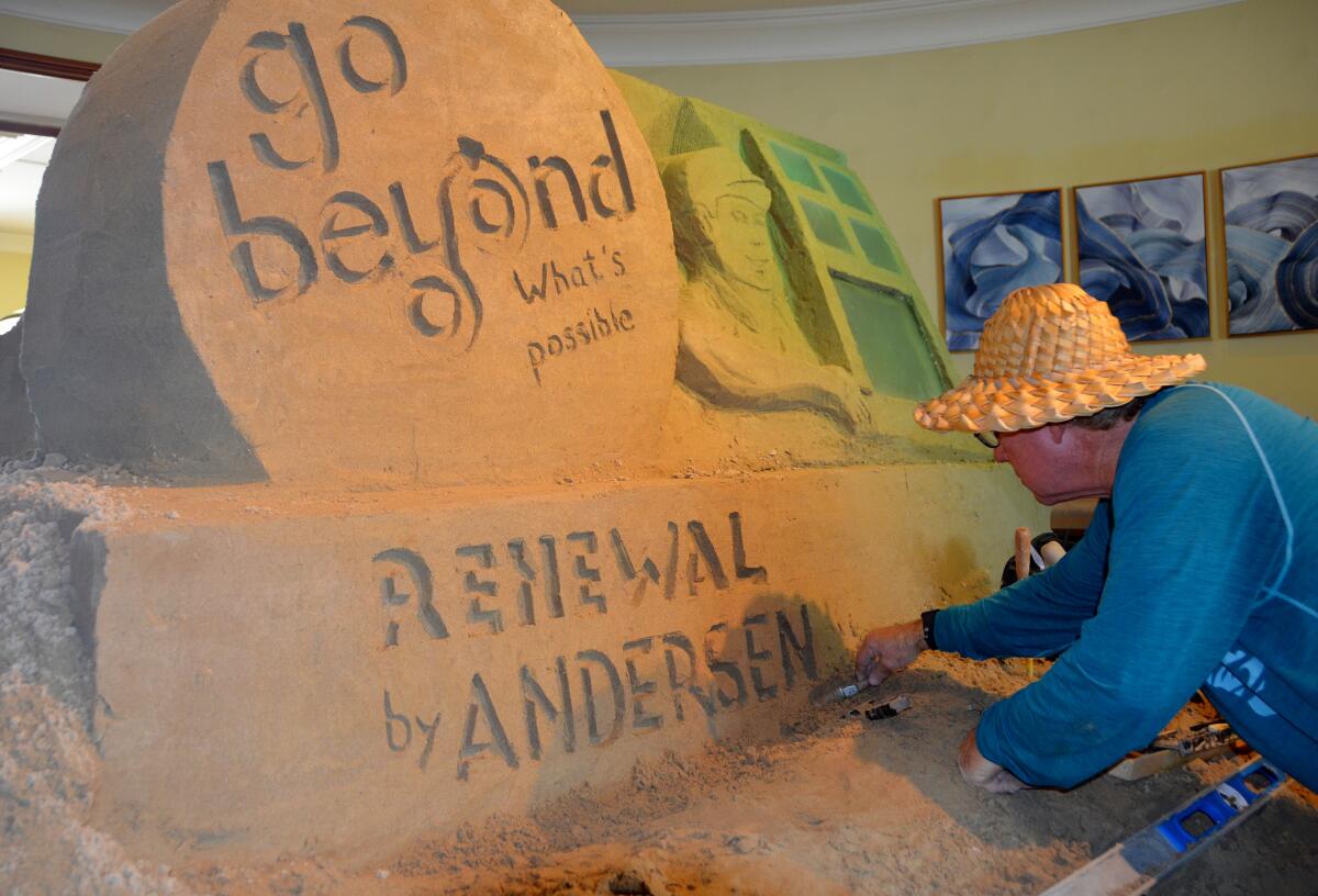 Chris Crosson carves out finishing touches on the Andersen Window sand sculpture.