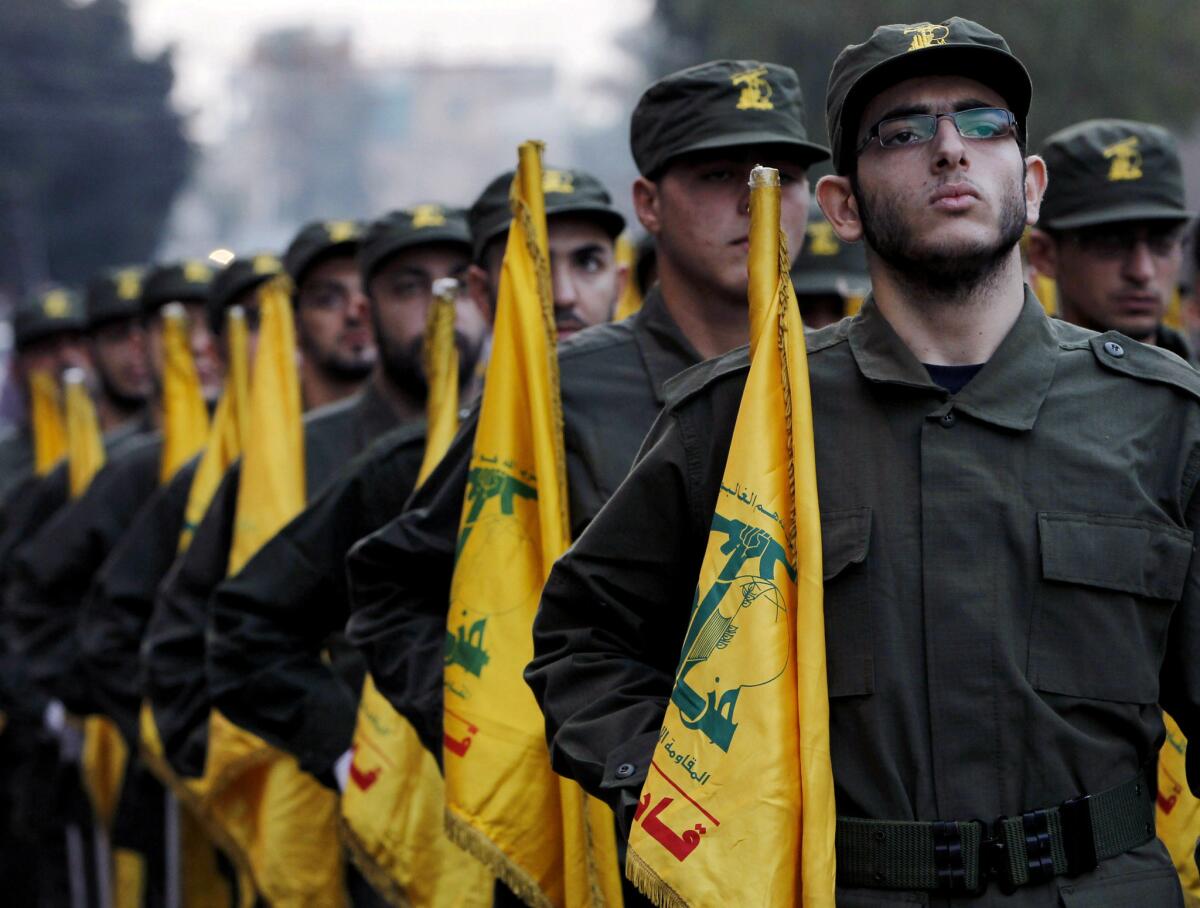 In this Nov. 12, 2010, file photo, Hezbollah fighters in Beirut hold the flag of the militant group as they parade during the opening of a cemetery for colleagues who died in fighting against Israel.