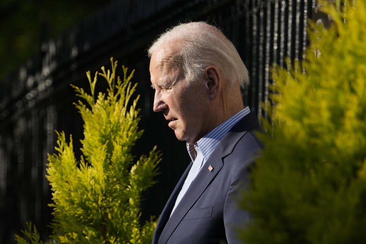 Side view of President Biden walking amid greenery.
