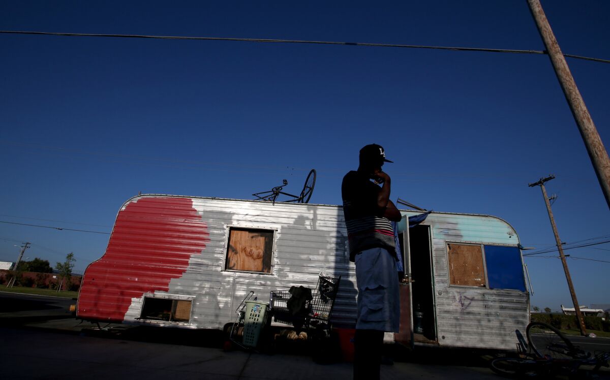 A man stands outside his battered trailer along Broadway in an unincorporated section of southern L.A. County. Shortly afterward, he was arrested for outstanding warrants and his home was towed away.