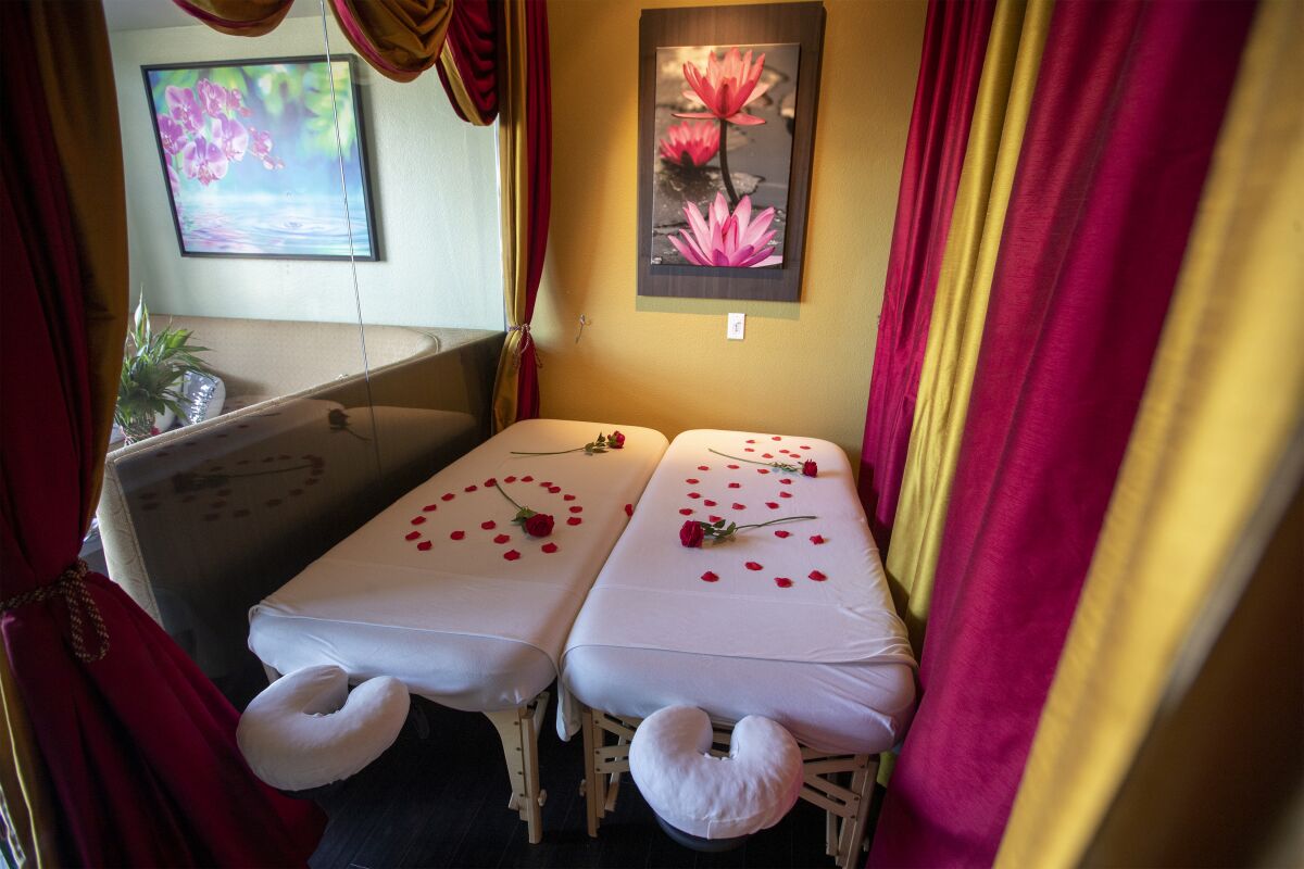 A view of empty couples massage room with rose petals on side-by-side massage beds