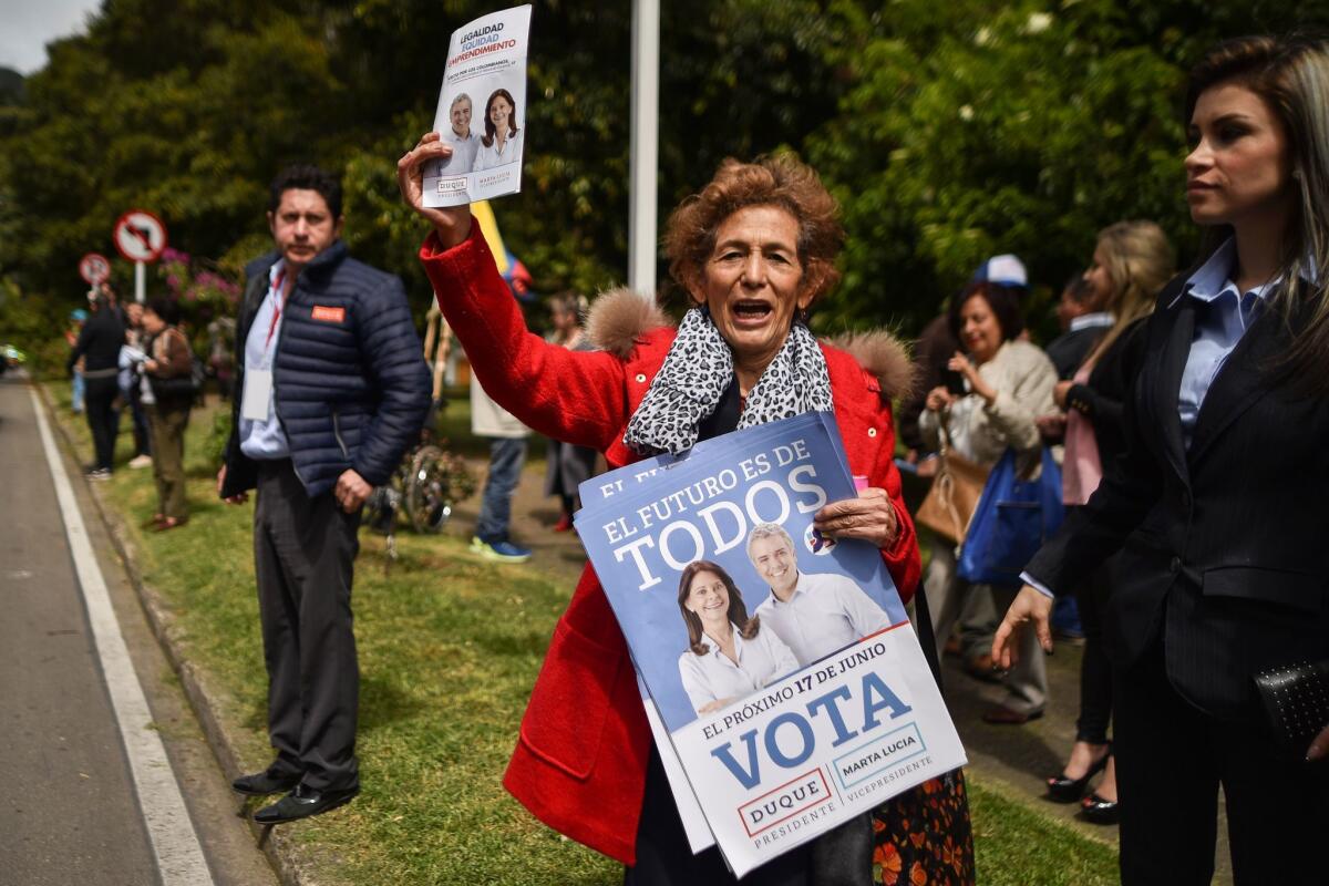 A supporter of Colombian presidential candidate Ivan Duque holds campaign posters in Bogota on Friday.