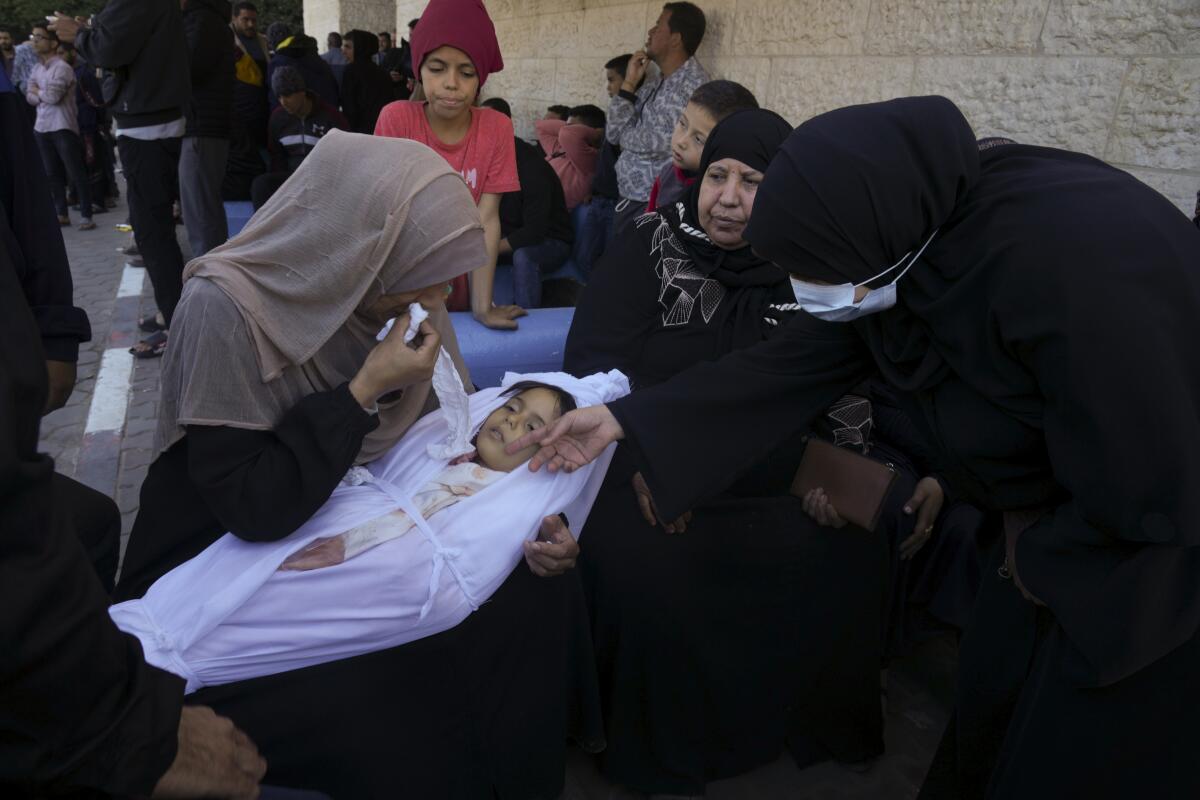 A mother cries for her daughter, wrapped in a white sheet, who was killed in the Israeli bombardment.