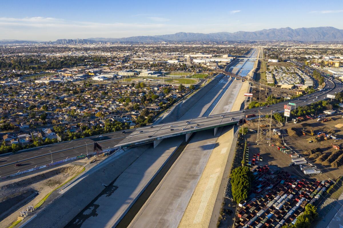 The nearly empty Los Angeles River flows beneath a freeway.
