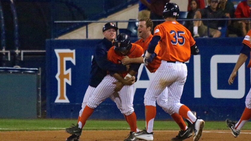 Cal State Fullerton's A.J. Kennedy, left, and Taylor Bryant, center right, mob teammate Jerrod Bravo following his walk-off walk in the 14th inning to lift the Titans to a 3-2 win over Arizona State in the Fullerton Regional on Sunday morning.