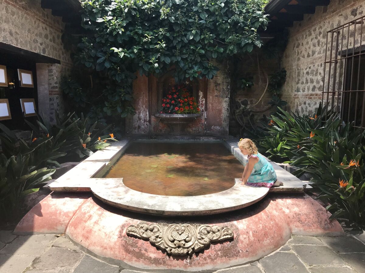 The reporter's daughter, Cora, plays at a fountain in a courtyard at Porta Hotel Antigua, Guatemala