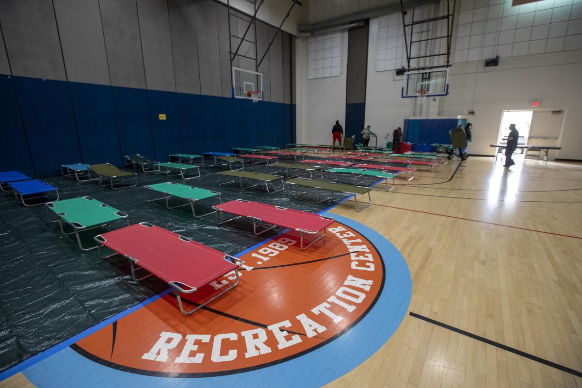 City workers and volunteers from the Salvation Army set up cots at the Westwood Recreation Center in Westwood. It is one of several shelters opening to accommodate homeless people during the coronavirus pandemic. 